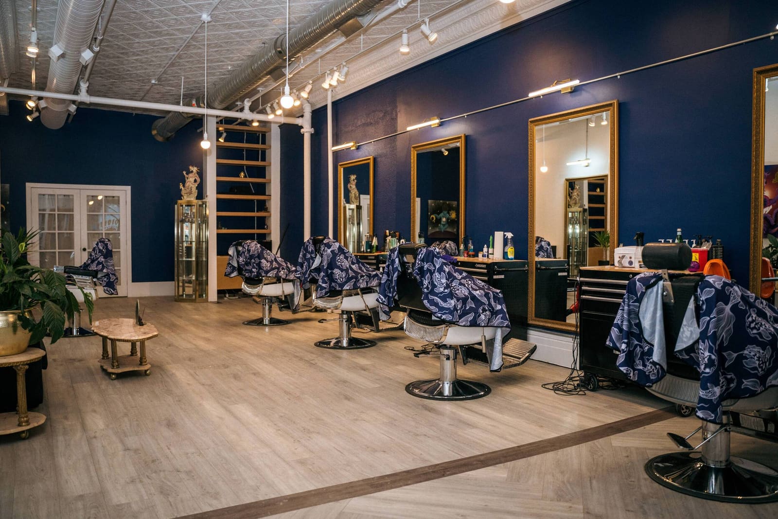 Inside Vision Studios: navy walls, gold-framed mirrors and barber chairs under a pressed-tin ceiling